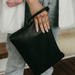 A woman holds onto a black vegan leather nappy wallet through the wristlet.