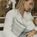 A mum wearing a stylish white blazer and metallic silver clutch rocks her baby to sleep.